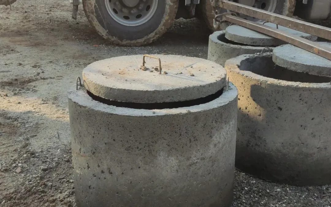 Rozładunek betonowych kręgów Fi 1000 z pokrywą z samochodu z żurawiem HDS na terenie budowy